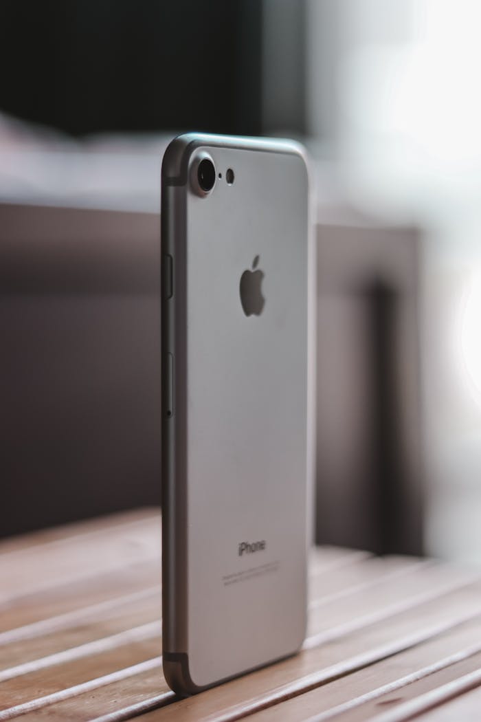 Close-up shot of a sleek smartphone standing on a wooden table, emphasizing design and technology.
