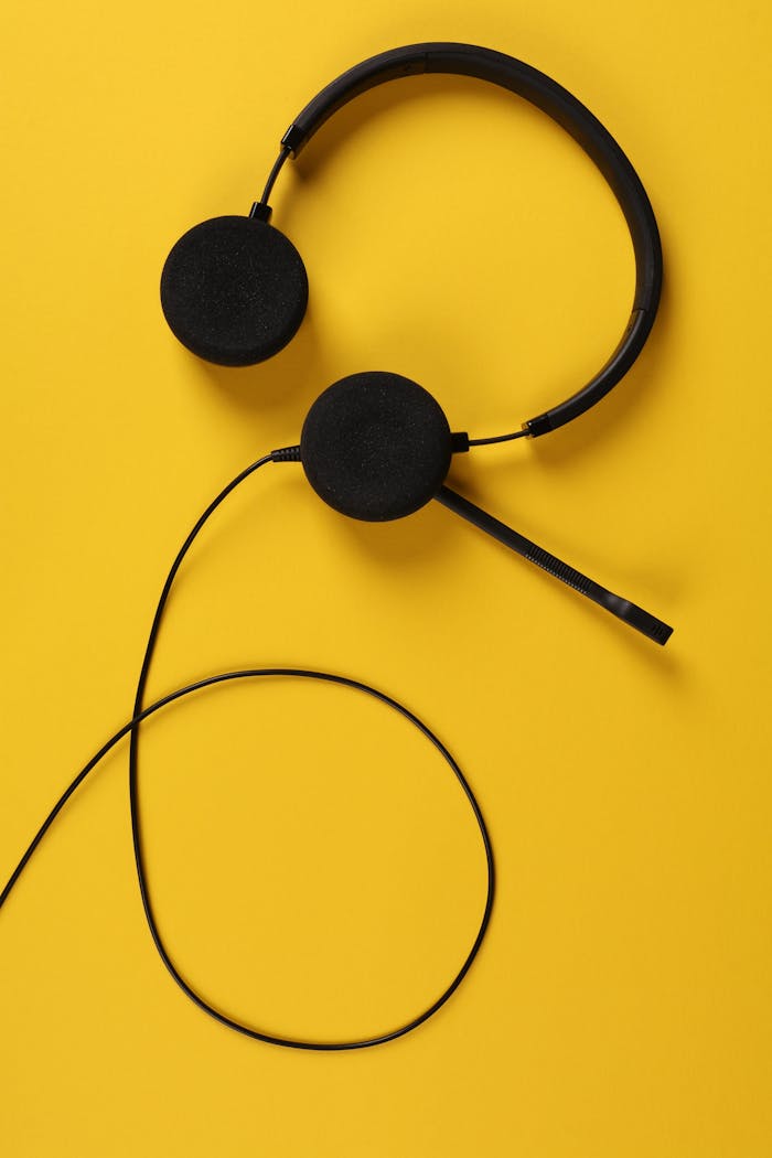 Top view of a black headset with extended microphone on a bold yellow background, perfect for tech and communication themes.